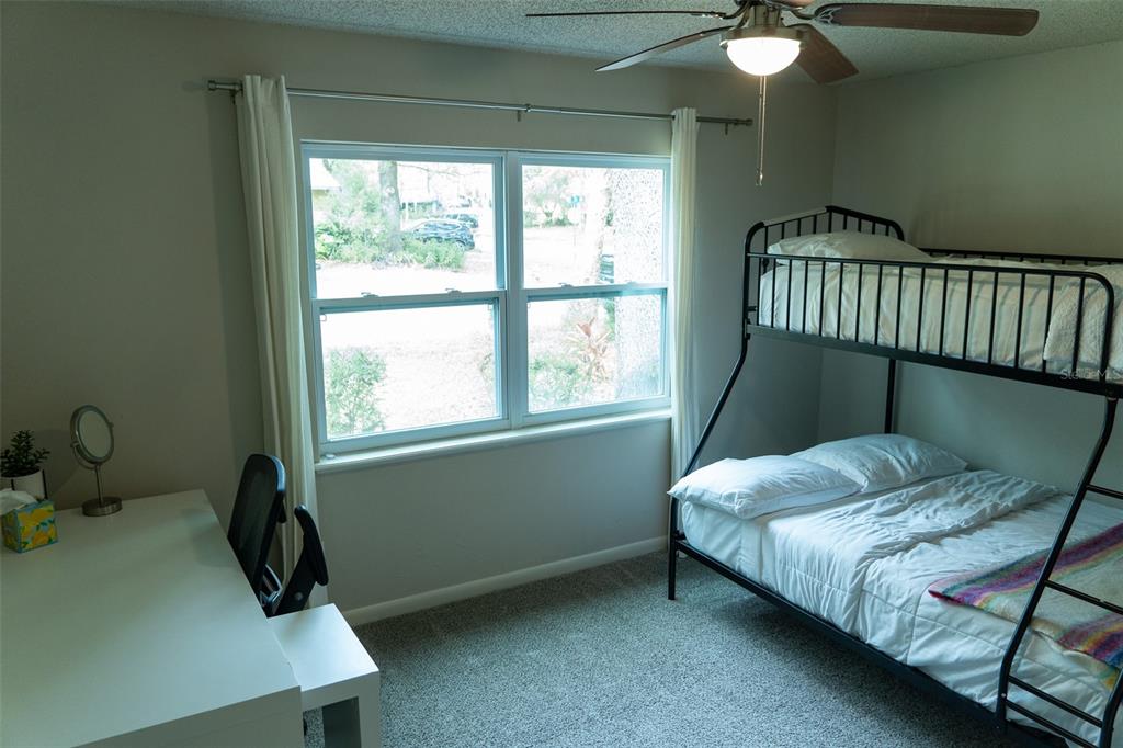 A bedroom features a bunk bed, a desk with a chair, and a large window — 8221 SW 13TH ROAD, GAINESVILLE, FL