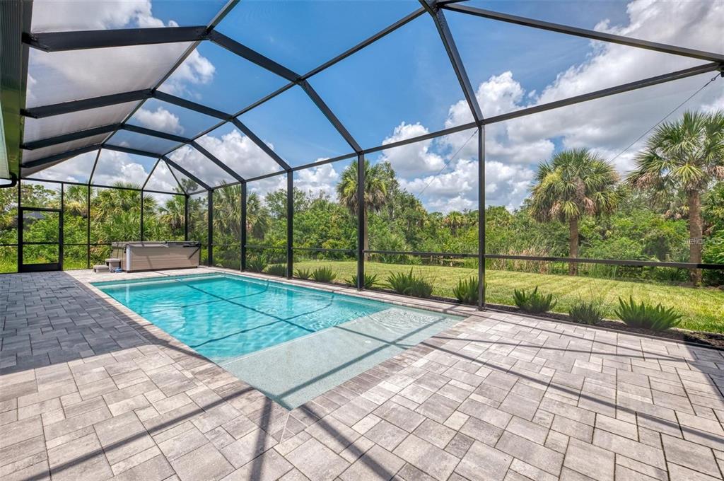 A screened-in patio features a rectangular swimming pool, a hot tub, and paver flooring — 2129 LORRAINE DRIVE, PORT CHARLOTTE, FL