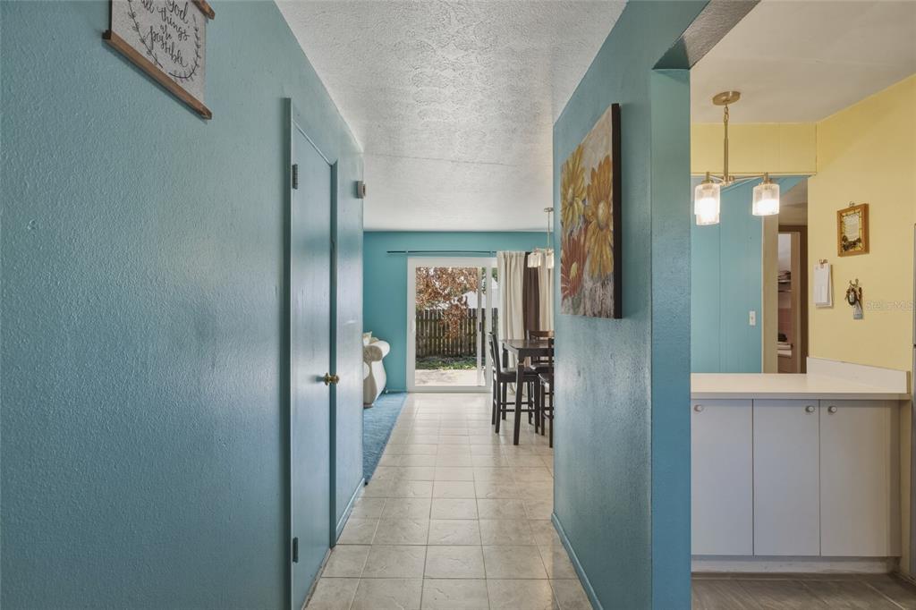 A hallway with tiled floors leads toward a dining area and a sliding glass door — 965 ALLENDALE STREET, TITUSVILLE, FL
