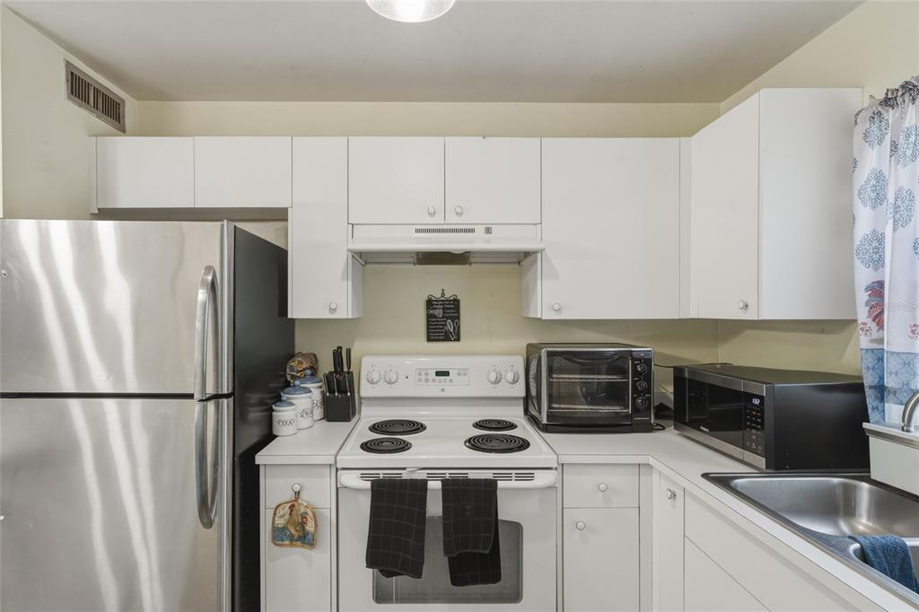 A kitchen features white cabinets, a stainless steel refrigerator, a white stove, and a microwave — 965 ALLENDALE STREET, TITUSVILLE, FL