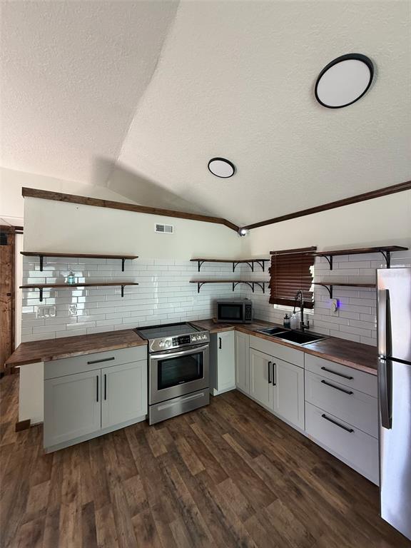 A kitchen features light gray cabinets, wood countertops, open shelving, and white subway tile backsplashes — 18312 HOLISTER RD, ORLANDO, FL