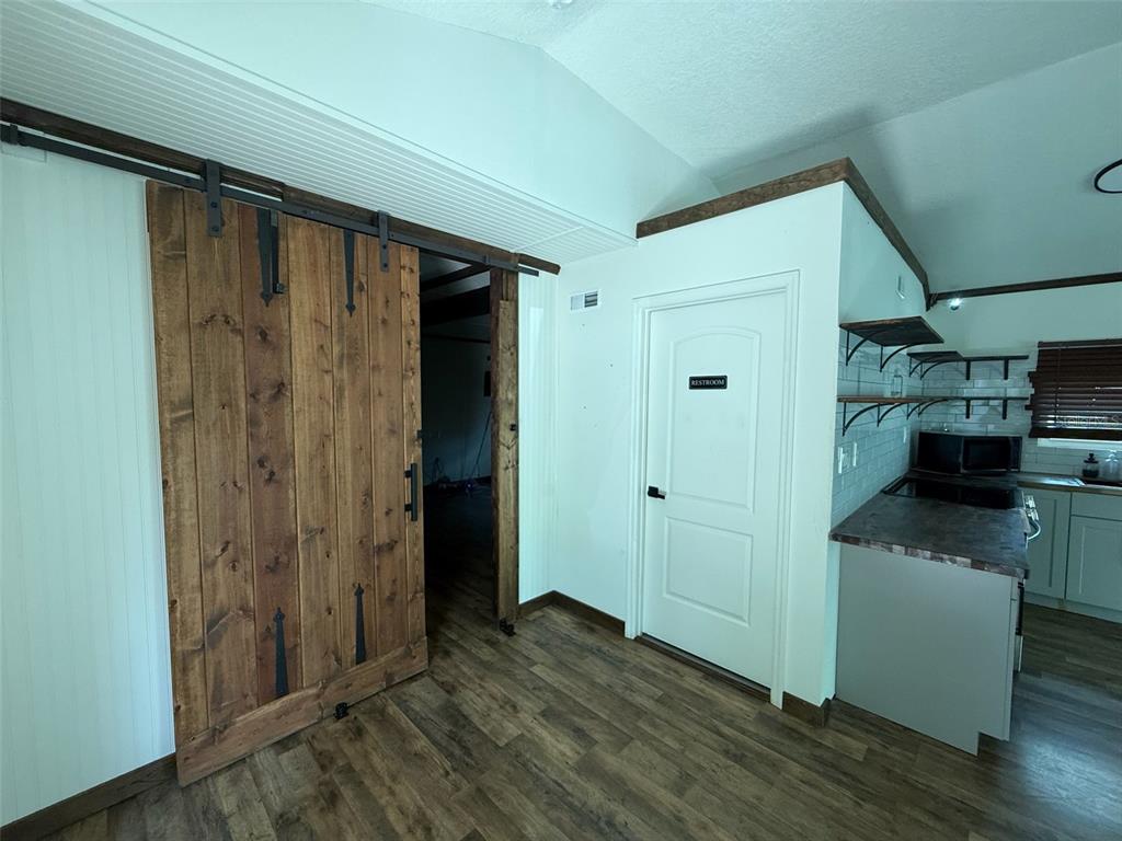 A room features a sliding barn door, a restroom door, and an adjacent kitchen area — 18312 HOLISTER RD, ORLANDO, FL