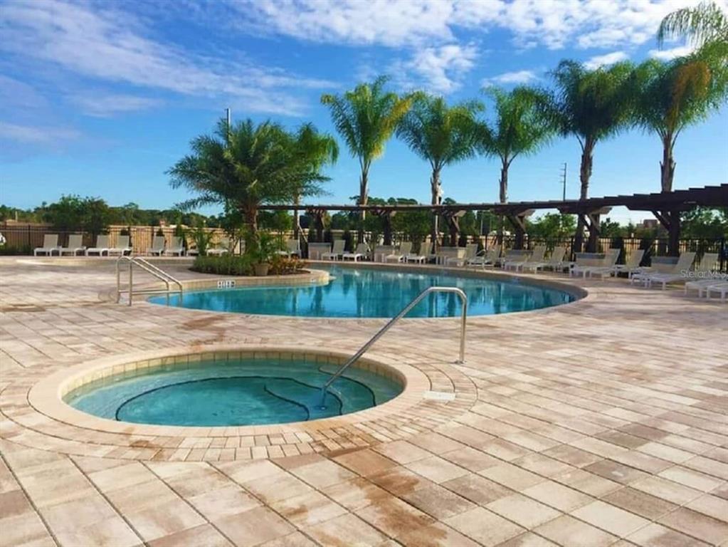 A circular hot tub sits on a paved deck in front of a swimming pool — 8933 SHINE DRIVE, KISSIMMEE, FL