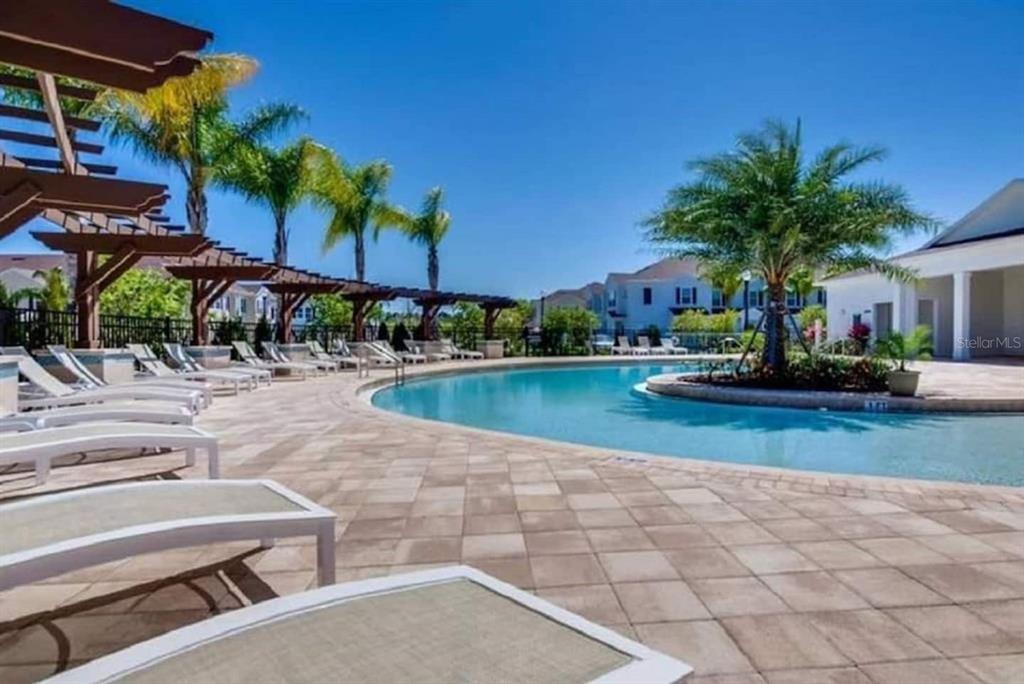 A swimming pool with lounge chairs and a wooden pergola on a paved pool deck — 8933 SHINE DRIVE, KISSIMMEE, FL
