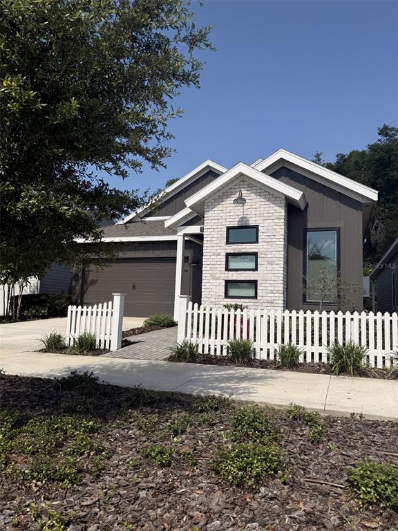 A modern house exterior features a white brick facade, dark siding, and a white picket fence — 1186 NW 132ND BOULEVARD, NEWBERRY, FL