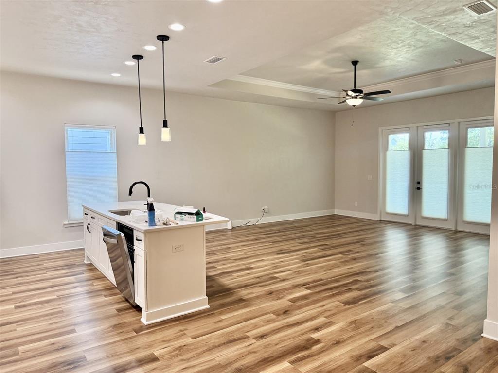 An open-concept kitchen and living area features wood-look flooring, a white island, and glass doors — 1186 NW 132ND BOULEVARD, NEWBERRY, FL