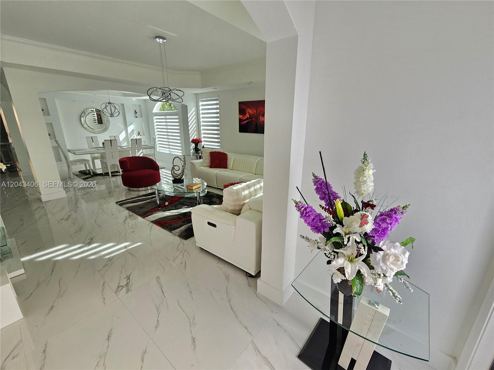 A bright living and dining area features white marble floors, modern furniture, and floral decor — 15561 SW 31st Ln # 0, Miami FL 33185, MIAMI, FL