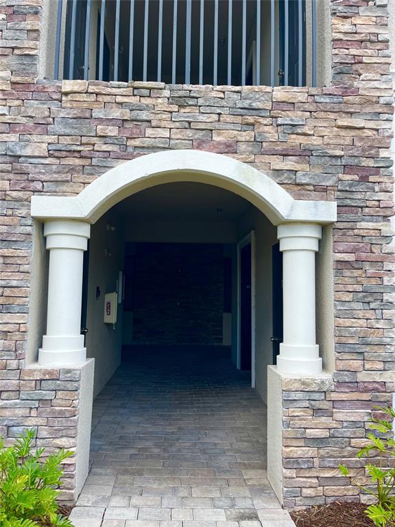 An arched entryway with white columns leads to a stone-paved walkway between two building entrances — 17108 VARDON TERRACE UNIT 401, BRADENTON, FL