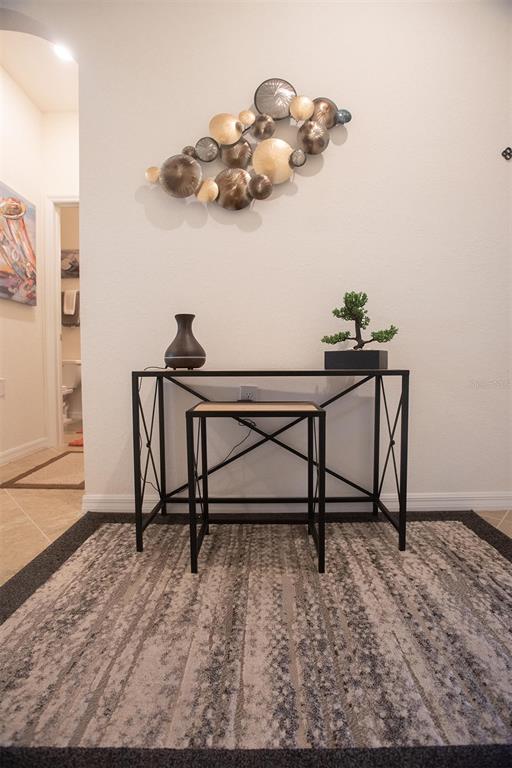 A console table with a stool sits on a rug beneath wall art in a hallway — 17108 VARDON TERRACE UNIT 401, BRADENTON, FL