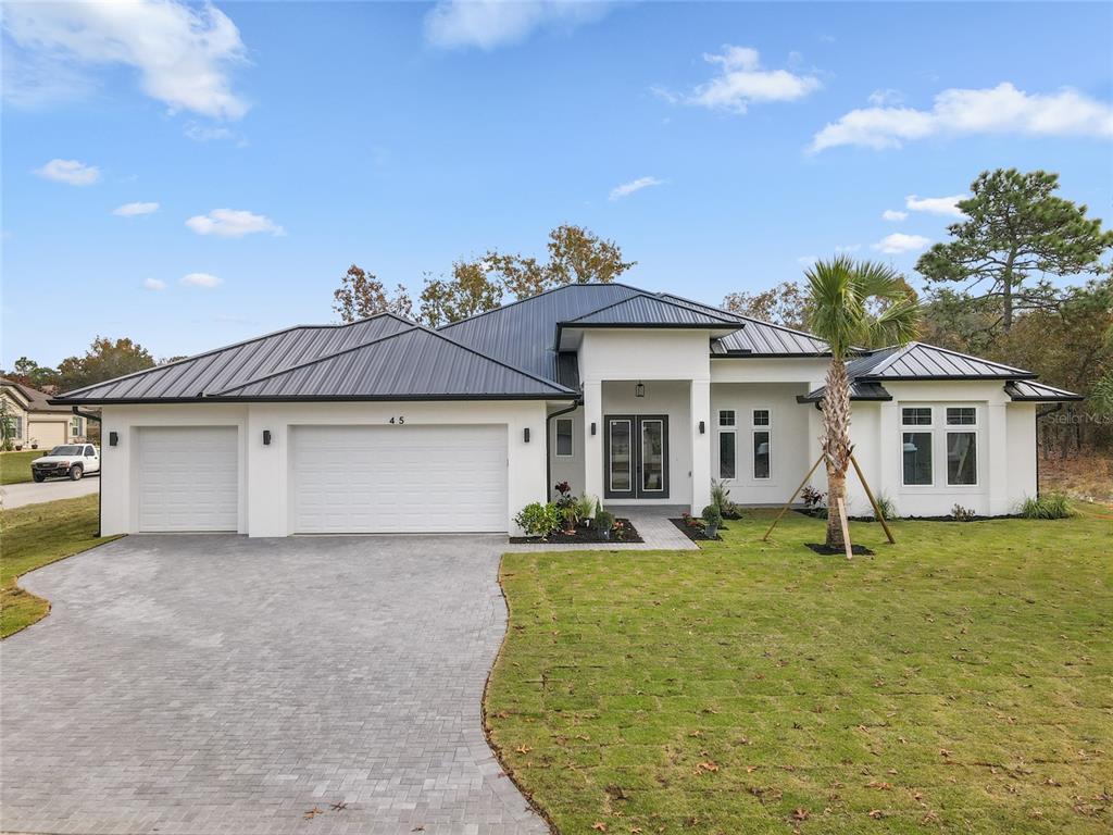 A single-story white house with a dark metal roof and a paved driveway — 45 VINCA STREET, HOMOSASSA, FL