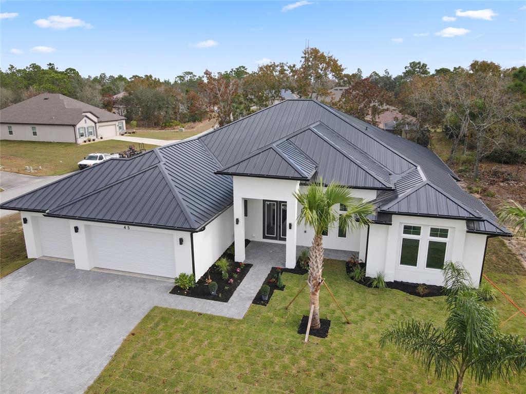 An aerial view of a modern white house with a dark metal roof and garage — 45 VINCA STREET, HOMOSASSA, FL