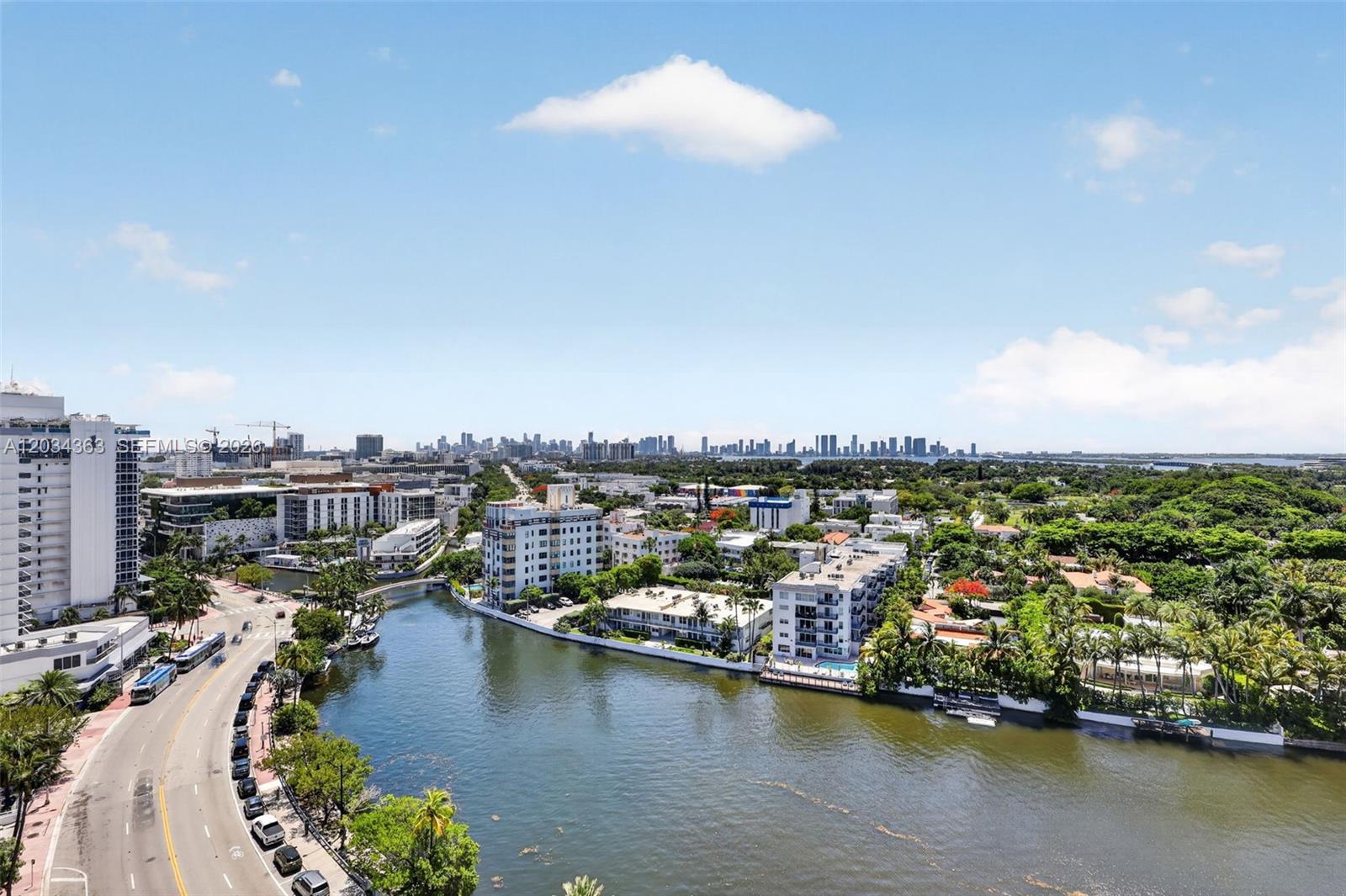 An aerial view shows a winding canal, surrounding buildings, and a distant city skyline — 2555 Collins Ave # 1812, Miami Beach FL 33140, MIAMI BEACH, FL