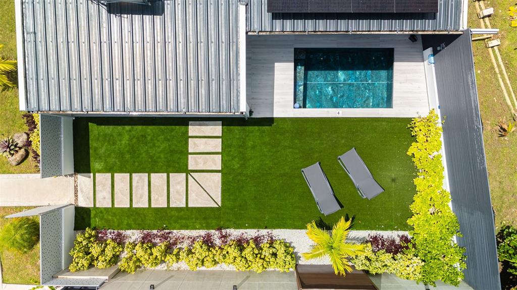 An aerial view shows a modern house with a pool, artificial lawn, and lounge chairs — PR-967 BO JIMENEZ KM. 1.5, RIO GRANDE, PR