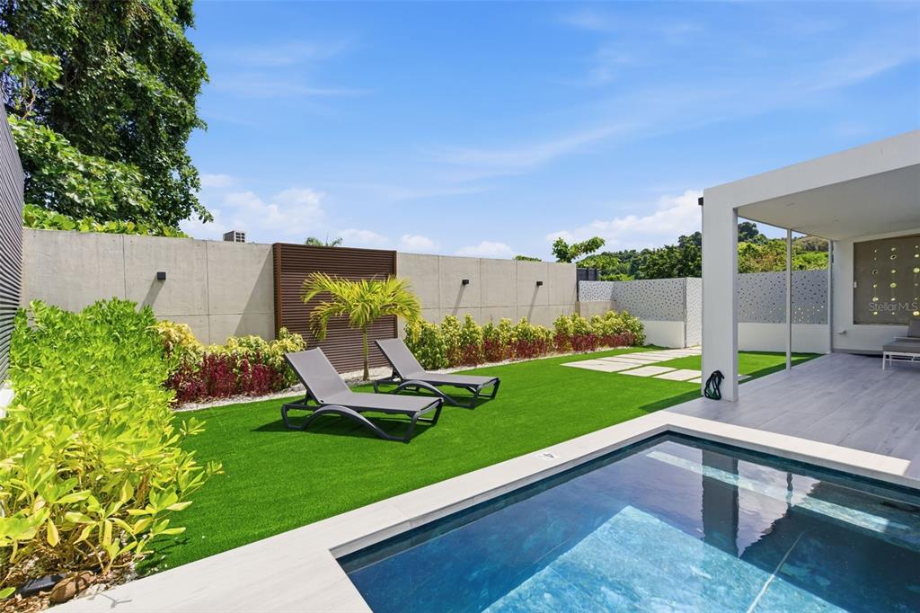 A modern backyard features a small swimming pool, two lounge chairs, and artificial turf — PR-967 BO JIMENEZ KM. 1.5, RIO GRANDE, PR
