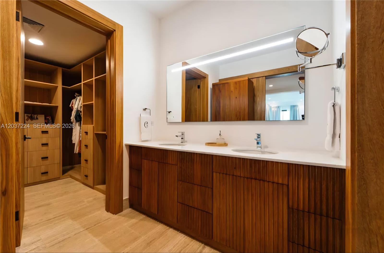 A bathroom with a double vanity, wood cabinets, and an adjacent walk-in closet — 0 Farralon, FL