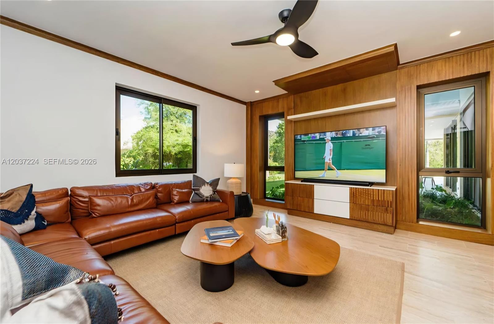 A living room features a leather sectional, wood-paneled media wall, and a modern ceiling fan — 0 Farralon, FL