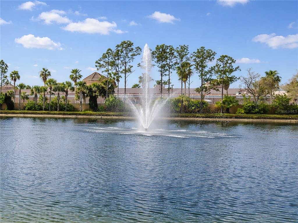 A water fountain sprays into a pond in front of a line of trees — 1731 AUBURN LAKES DRIVE UNIT 24, VENICE, FL