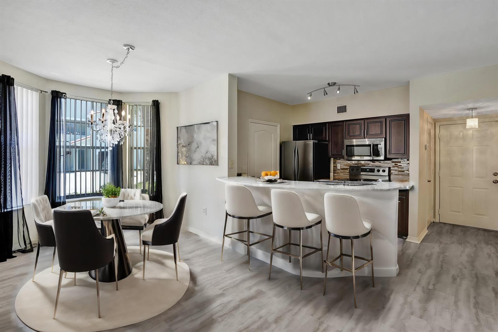 A dining area with a round table and a kitchen featuring dark cabinets and bar seating — 708 Belmont Place, Boynton Beach FL 33436, BOYNTON BEACH, FL