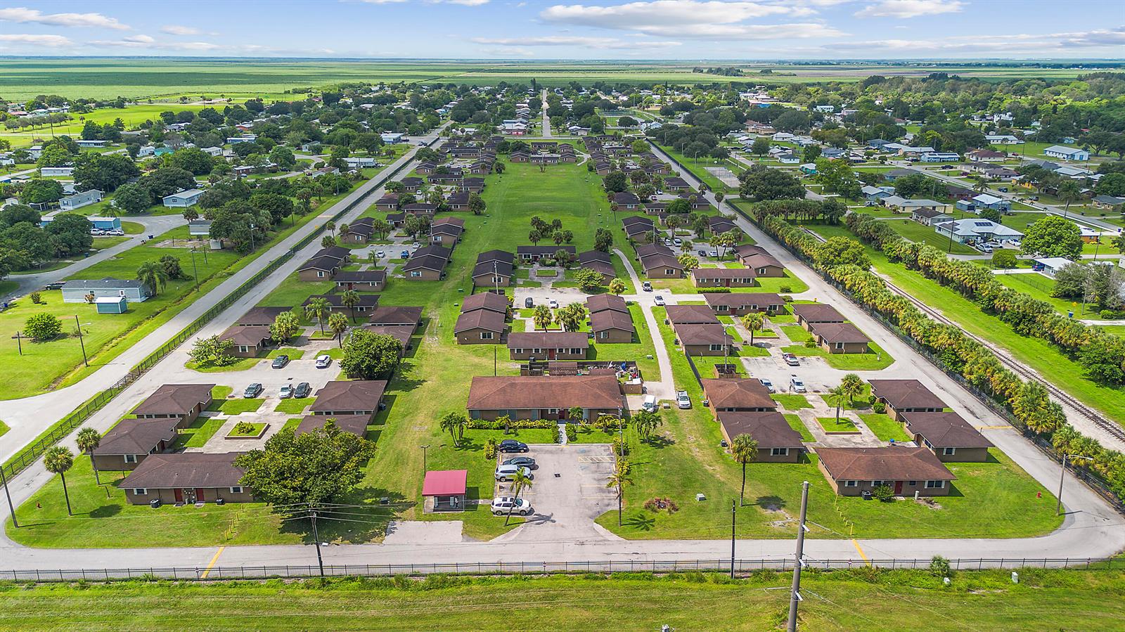 An aerial view shows a residential complex with multiple single-story buildings surrounded by green lawns — 700 Harlem Tenants Circle, Clewiston FL 33440, CLEWISTON, FL