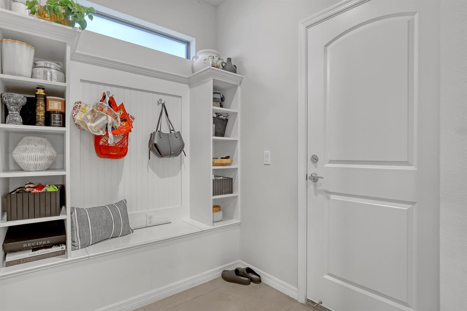 A white mudroom features built-in shelving, a bench with a striped pillow, and a door — 4740 Chantilly, Lake Worth FL 33467, LAKE WORTH, FL