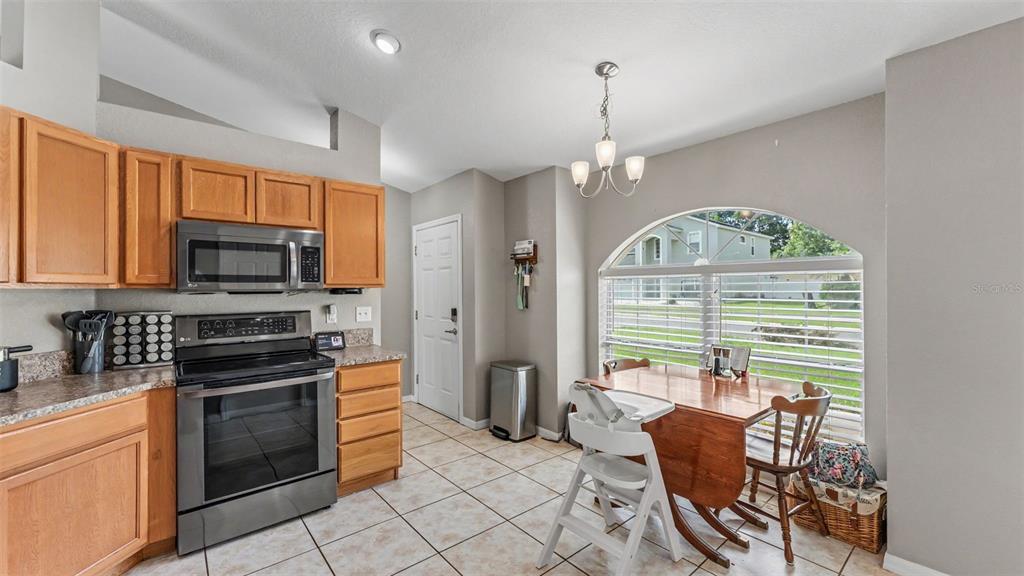 A kitchen with wood cabinets, stainless steel appliances, and a dining area by a window — 1320 NORMANDY HEIGHTS CIRCLE, WINTER HAVEN, FL