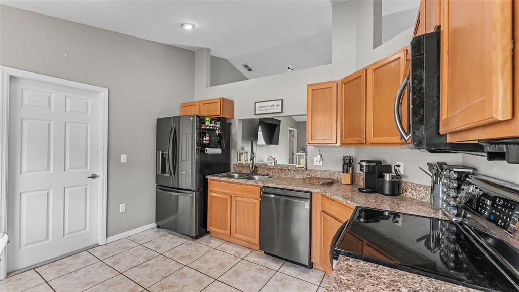 A kitchen features wood cabinets, granite countertops, stainless steel appliances, and tile flooring — 1320 NORMANDY HEIGHTS CIRCLE, WINTER HAVEN, FL