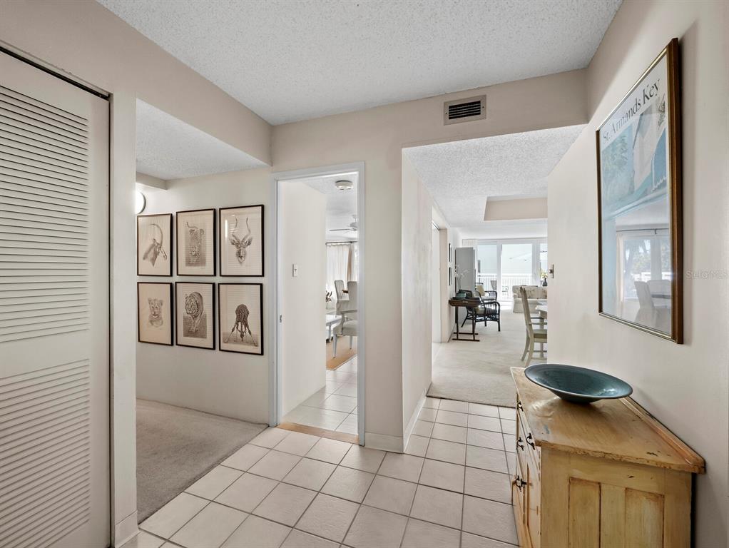 A tiled entryway leads to a hallway with framed art and a view into living areas — 5055 GULF OF MEXICO DRIVE UNIT 421, LONGBOAT KEY, FL