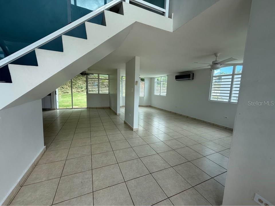 An open-concept living area features light tile flooring, a staircase, and multiple windows — 15 CALLE MARINA, CABO ROJO, PR