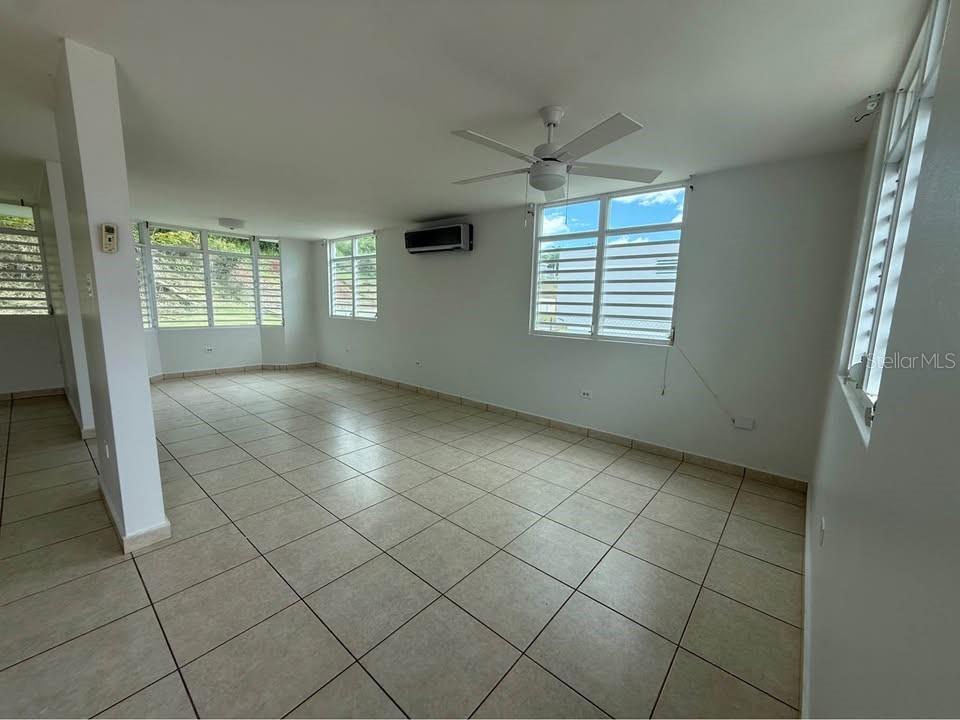 An empty room with light-colored tile flooring, a ceiling fan, and multiple windows — 15 CALLE MARINA, CABO ROJO, PR