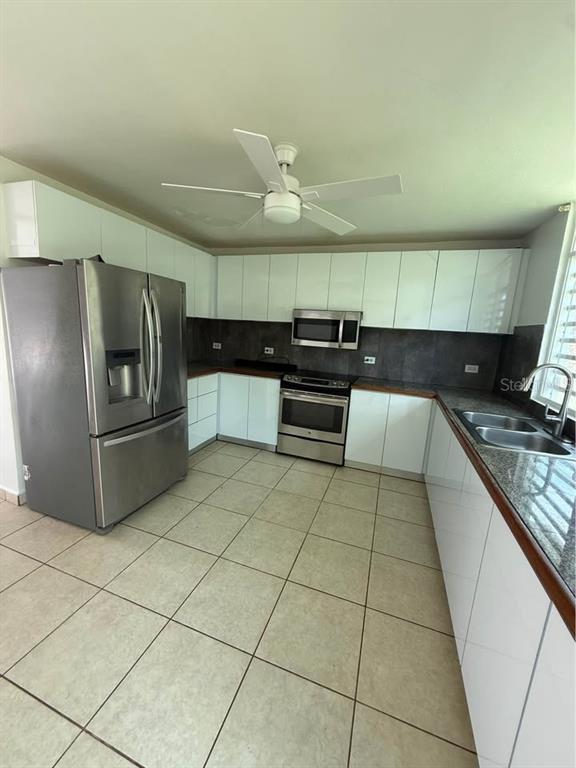 A kitchen features white cabinets, stainless steel appliances, dark countertops, and light-colored floor tiles — 15 CALLE MARINA, CABO ROJO, PR