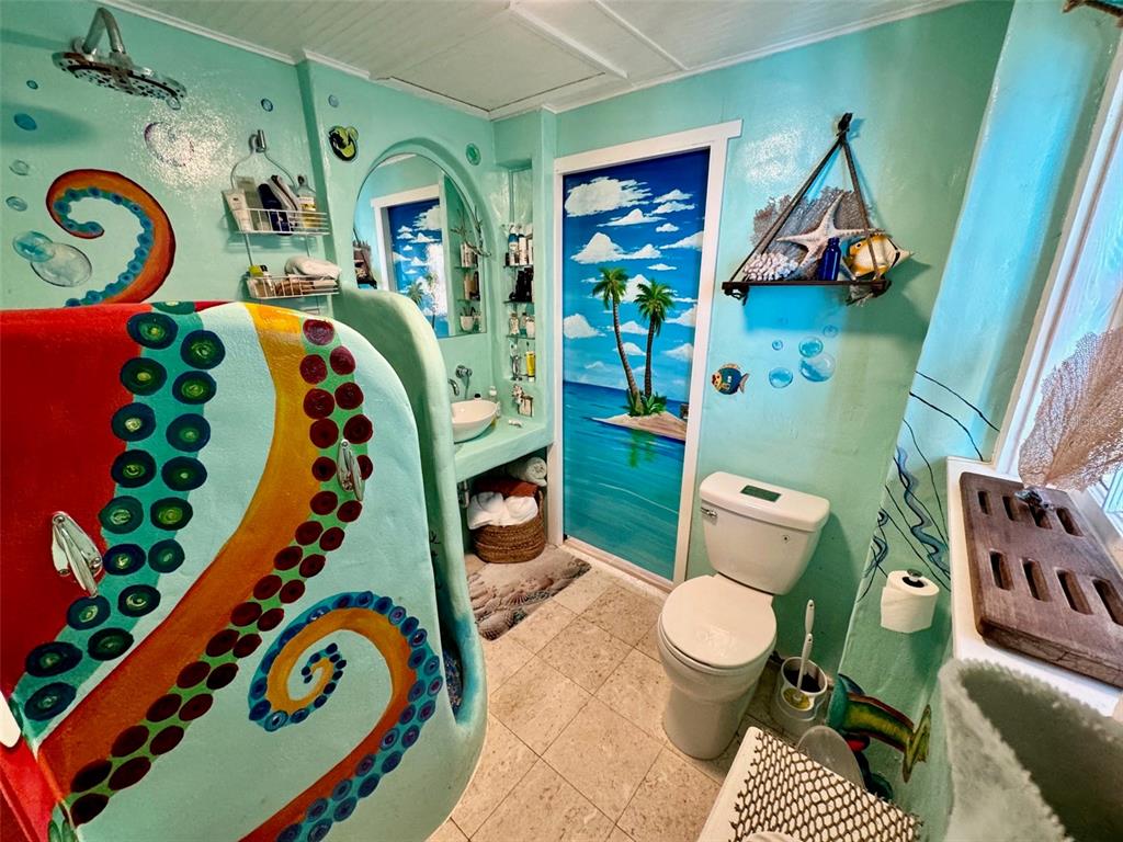 A whimsical bathroom features a large octopus-themed shower enclosure, tropical wall murals, and light-colored tile — 3022 56TH STREET S, GULFPORT, FL
