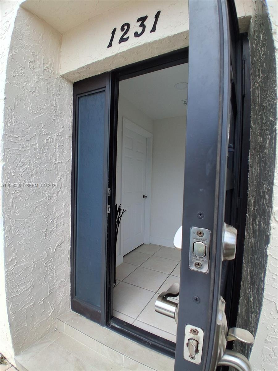 An open front door reveals a tiled entryway with a white interior door — 1231 SW 136th Pl # A, Miami FL 33184, MIAMI, FL