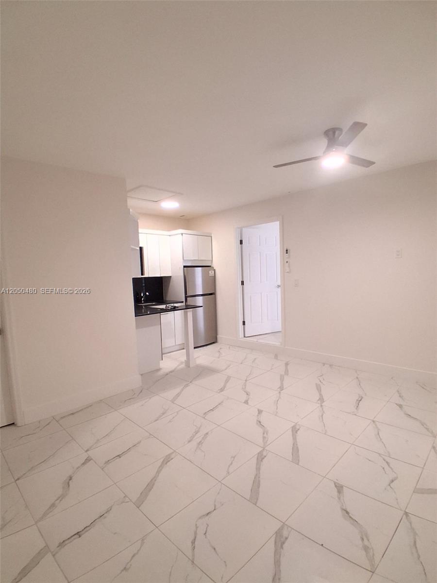 A kitchen with white cabinets and stainless steel appliances opens into a tiled living area — 1231 SW 136th Pl # A, Miami FL 33184, MIAMI, FL