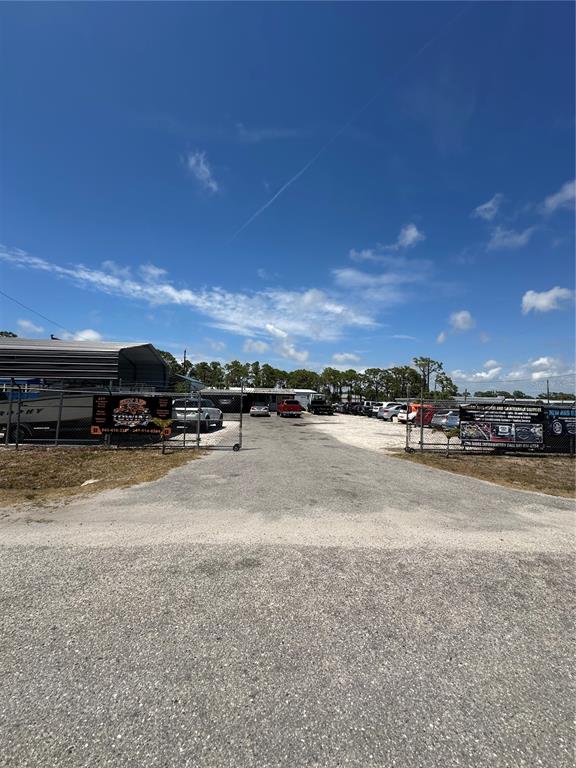 A gravel lot leads to a fenced storage area with several parked vehicles and buildings — 54 HARVARD STREET, ENGLEWOOD, FL