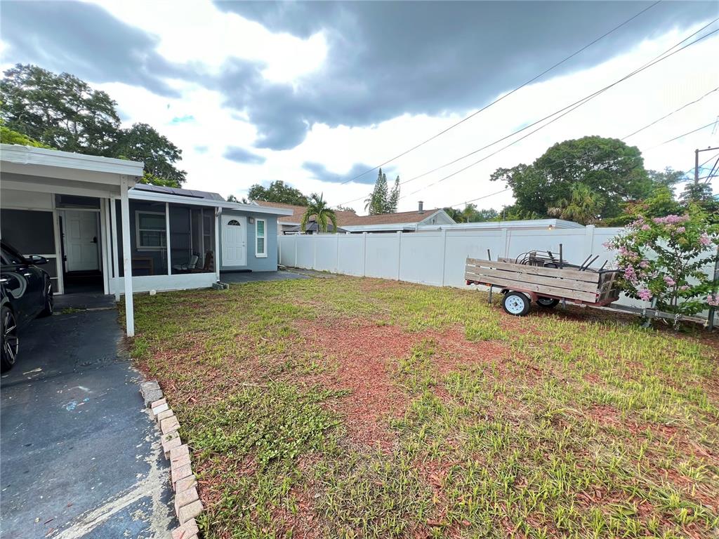 A backyard features a paved driveway, a covered patio, a white vinyl fence, and a trailer — 3806 6TH AVENUE N UNIT 1/2, ST PETERSBURG, FL