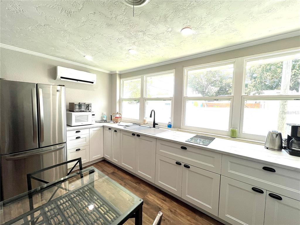 A kitchen features white cabinets, stainless steel appliances, a glass-top table, and large windows — 3806 6TH AVENUE N UNIT 1/2, ST PETERSBURG, FL
