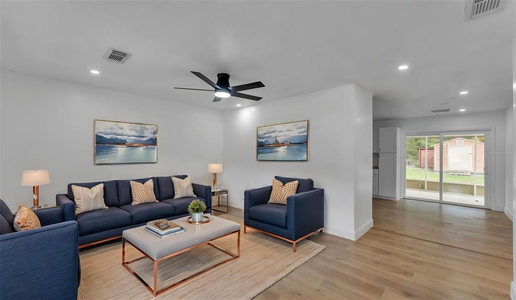 A living room features a blue sofa, matching armchairs, a coffee table, and wood flooring — 3781 N HIAWATHA TERRACE, CRYSTAL RIVER, FL