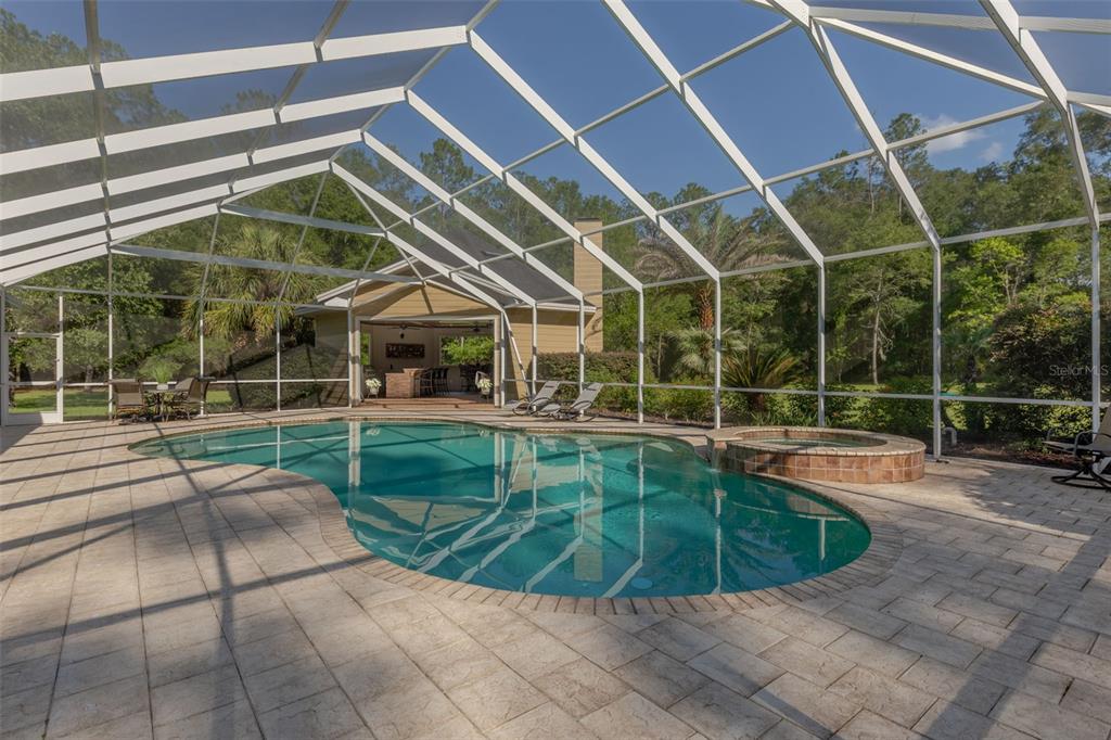 A swimming pool and hot tub are enclosed within a screened lanai on a patio — 19103 NW 72ND AVENUE, ALACHUA, FL