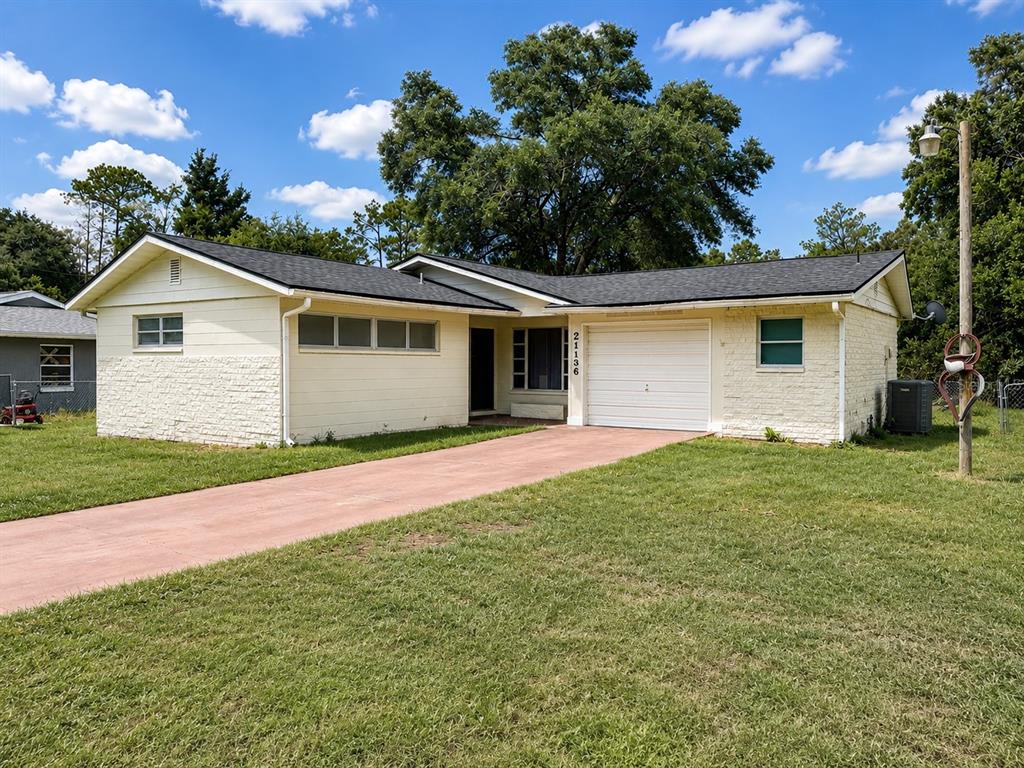 A single-story house with a light-colored brick exterior, a garage, and a red driveway — 21136 SW HONEYSUCKLE STREET, DUNNELLON, FL