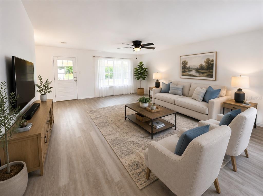A bright living room features light wood floors, a beige sofa, two armchairs, and a television — 21136 SW HONEYSUCKLE STREET, DUNNELLON, FL