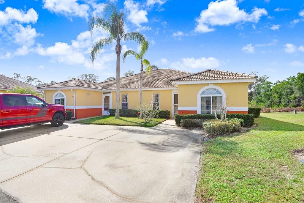 A single-story yellow house with a red trim, tile roof, and a concrete driveway — 116 OCEAN BLUFF DRIVE, KISSIMMEE, FL