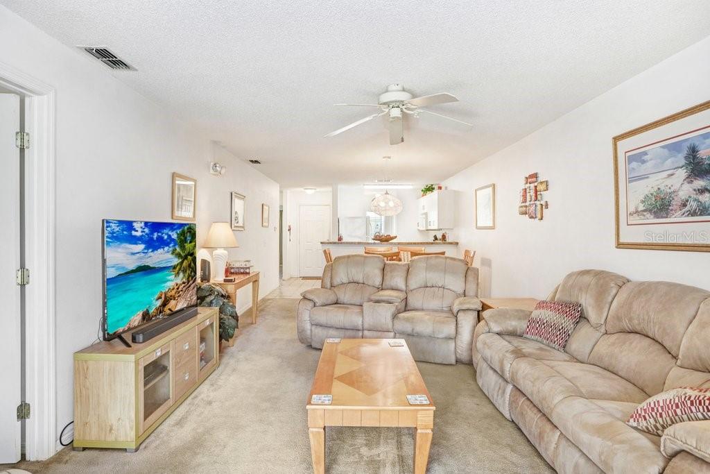A living room features beige carpet, two tan reclining sofas, and a wooden coffee table — 116 OCEAN BLUFF DRIVE, KISSIMMEE, FL
