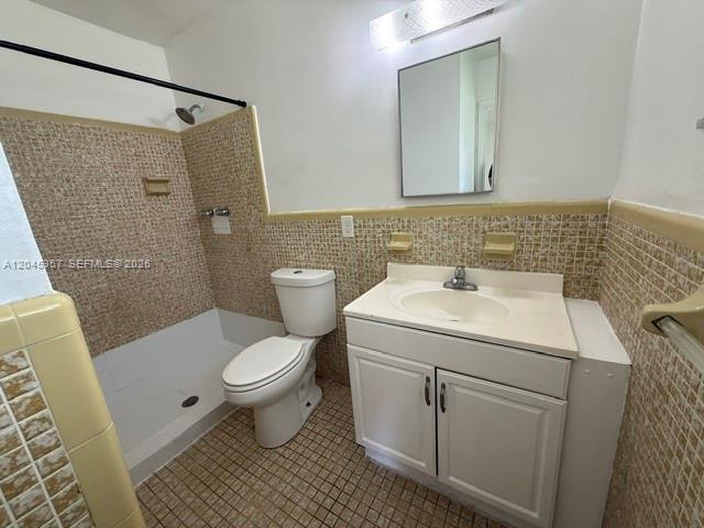 A bathroom features a white vanity, a toilet, and a shower stall with tan tiling — 5946 Mckinley St # B, Hollywood FL 33021, HOLLYWOOD, FL