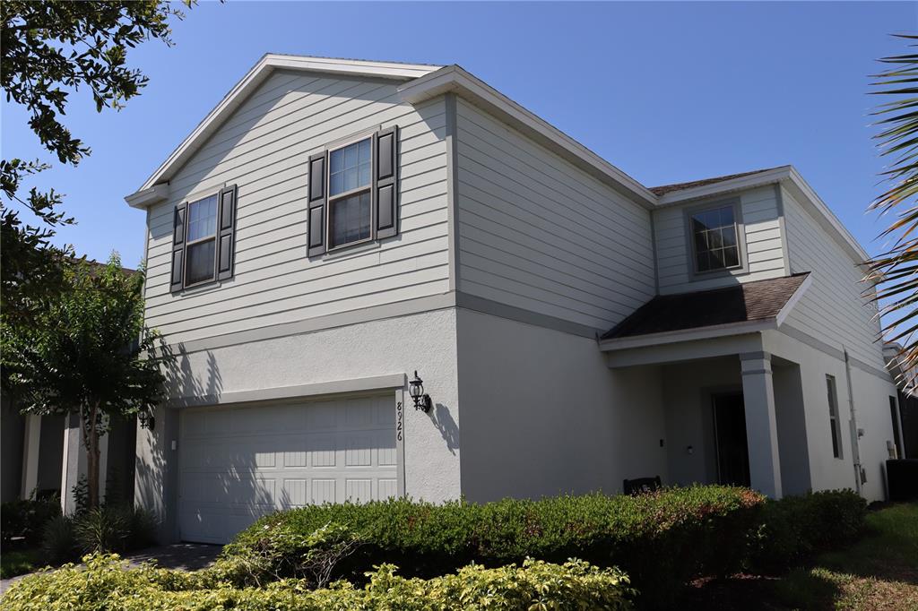 A two-story house with light-colored siding, a garage, and a covered front entrance — 8926 ZURICH LANE, KISSIMMEE, FL