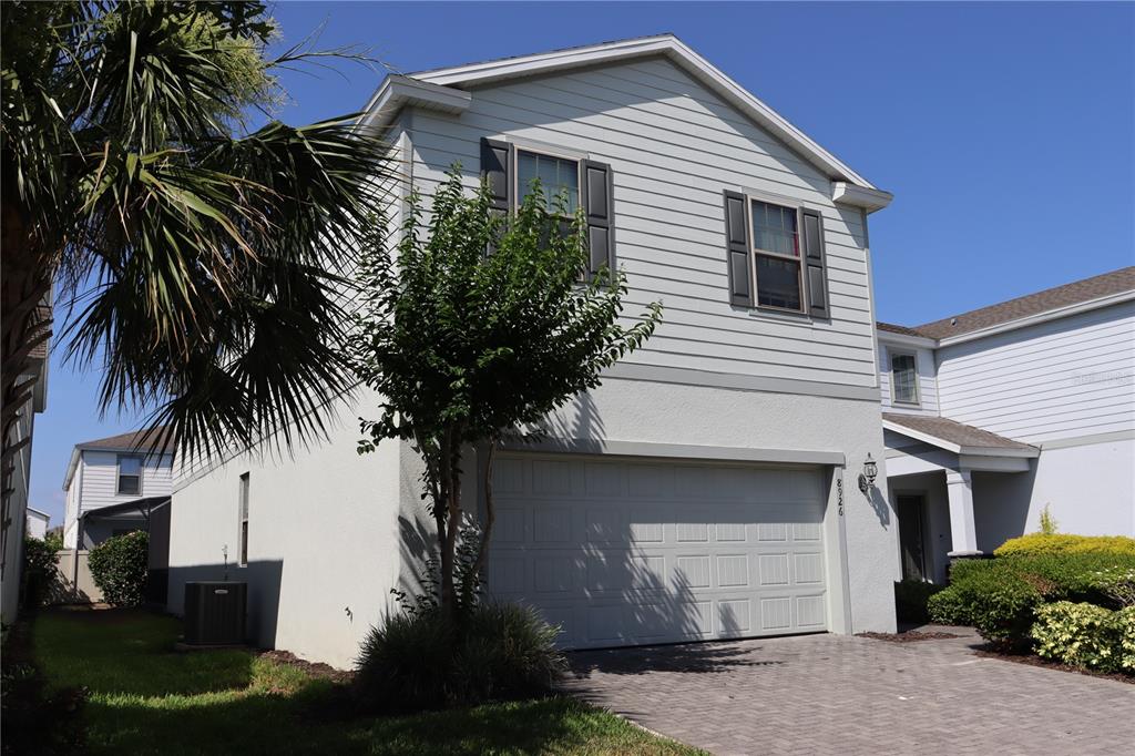 A two-story house features light gray siding, a two-car garage, and a paved driveway — 8926 ZURICH LANE, KISSIMMEE, FL