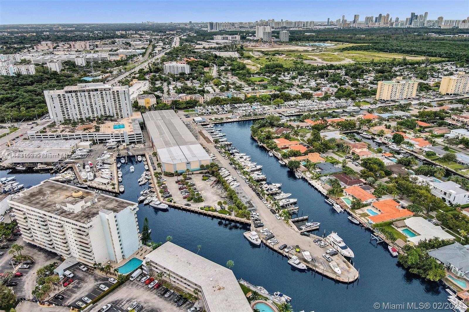 An aerial view shows a marina with numerous docked boats surrounded by residential buildings and greenery — 13499 Biscayne Blvd # 1513, North Miami FL 33181, NORTH MIAMI, FL