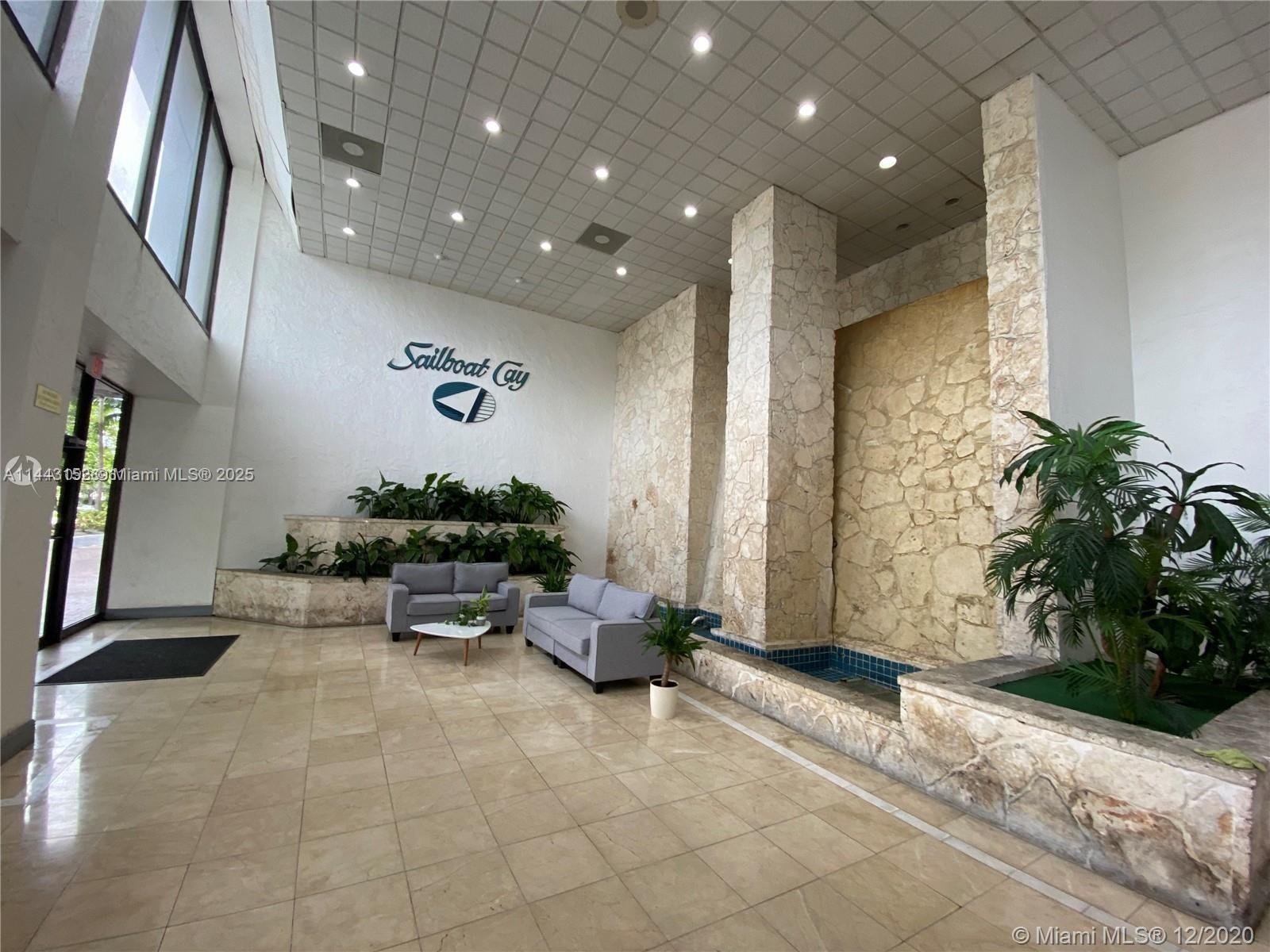 The lobby features a stone water feature, tiled flooring, and a seating area — 13499 Biscayne Blvd # 1513, North Miami FL 33181, NORTH MIAMI, FL