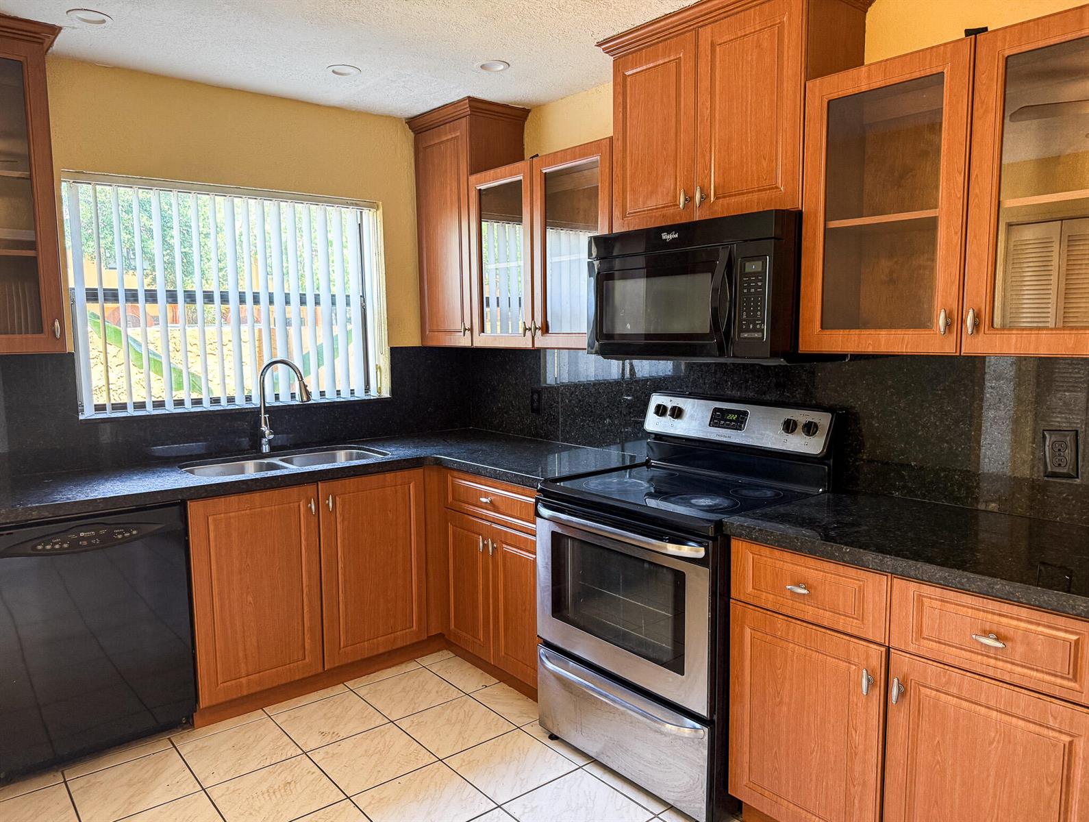 A kitchen featuring wood cabinets, black granite countertops, stainless steel appliances, and tile flooring — 4567 NW 90th Avenue, Sunrise FL 33351, SUNRISE, FL
