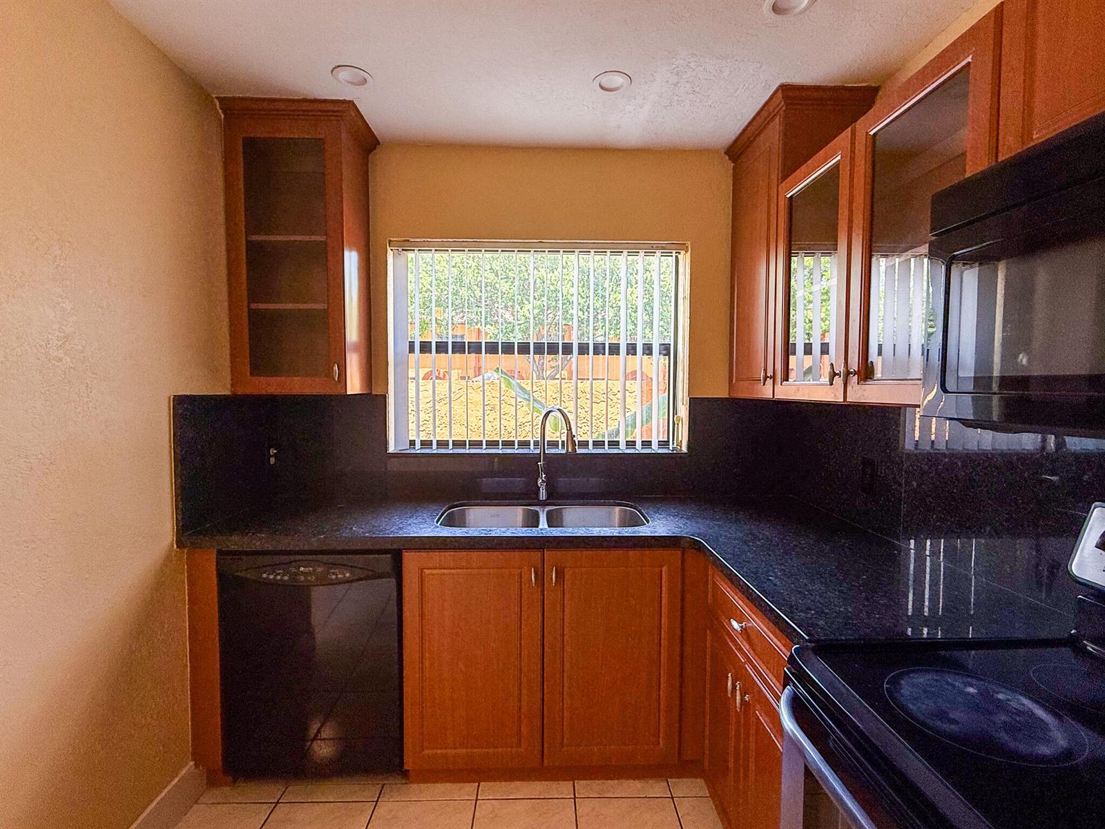 A kitchen features wood cabinets, black granite countertops, a double sink, and a black dishwasher — 4567 NW 90th Avenue, Sunrise FL 33351, SUNRISE, FL
