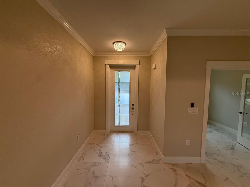 A foyer features marble-look tile flooring, a glass-paneled front door, and a decorative ceiling light — 14396 & 14422 CHAMBERLAIN BOULEVARD, PORT CHARLOTTE, FL